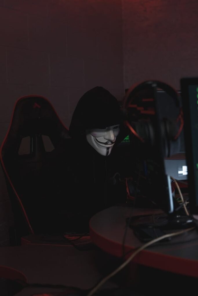 A hacker in a Guy Fawkes mask working on cybersecurity at night, conveying secrecy.